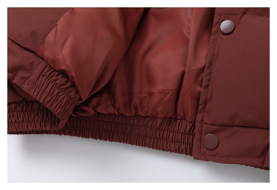 Close-up of the burgundy jacket's elasticized hem, sleeve cuff, and front snap placket.