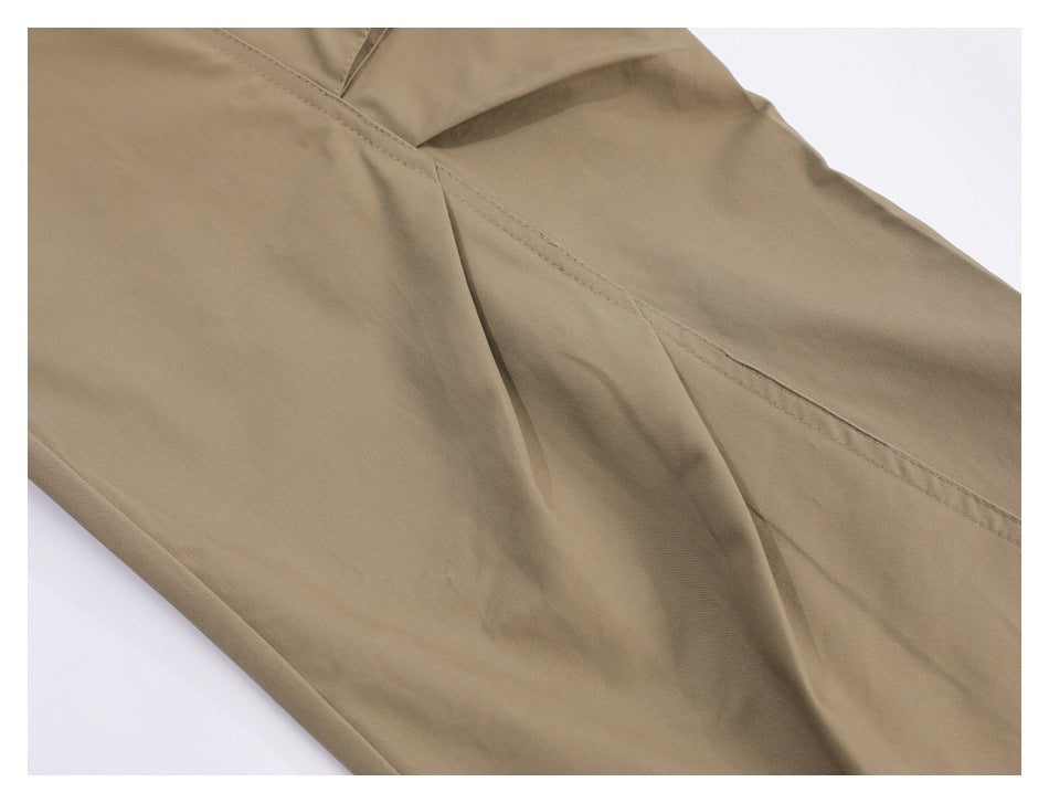 Close-up of khaki trousers showing a curved seam and stitched panel.