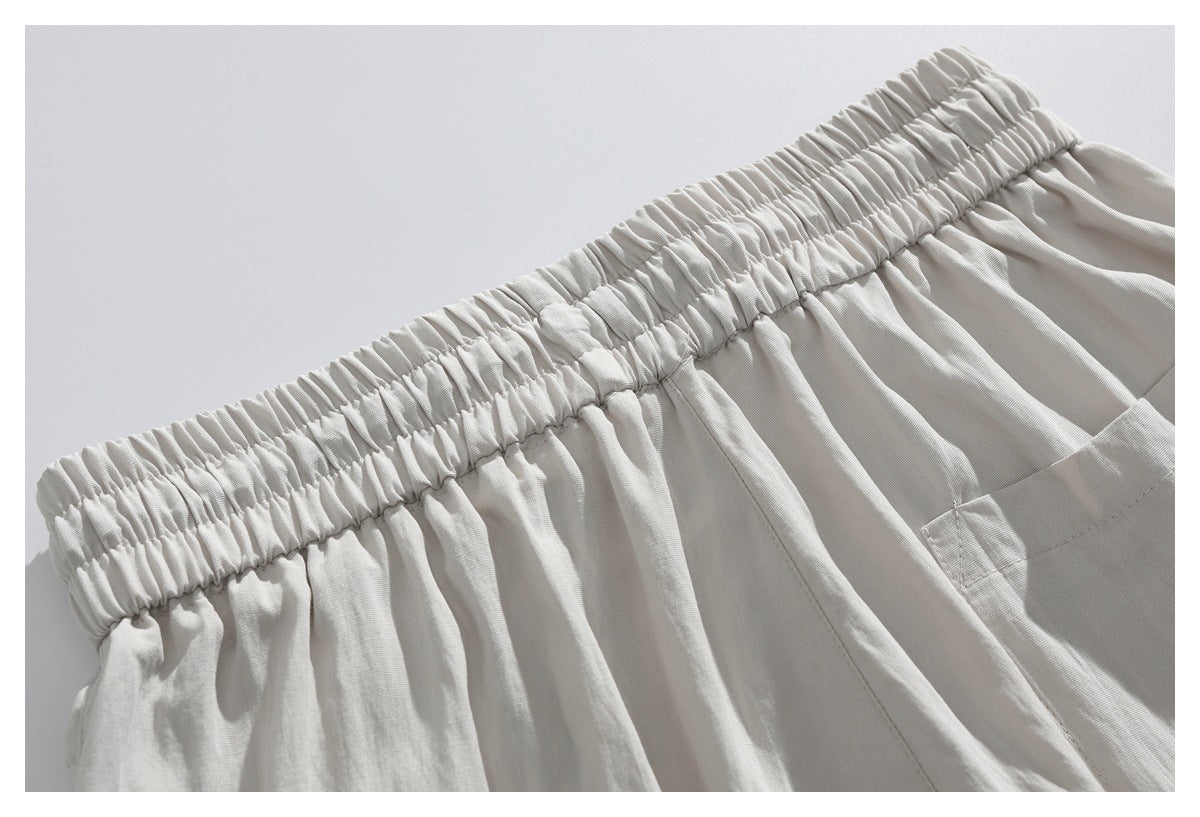 Close-up of cream bottoms showing the gathered elastic waistband and a patch pocket.
