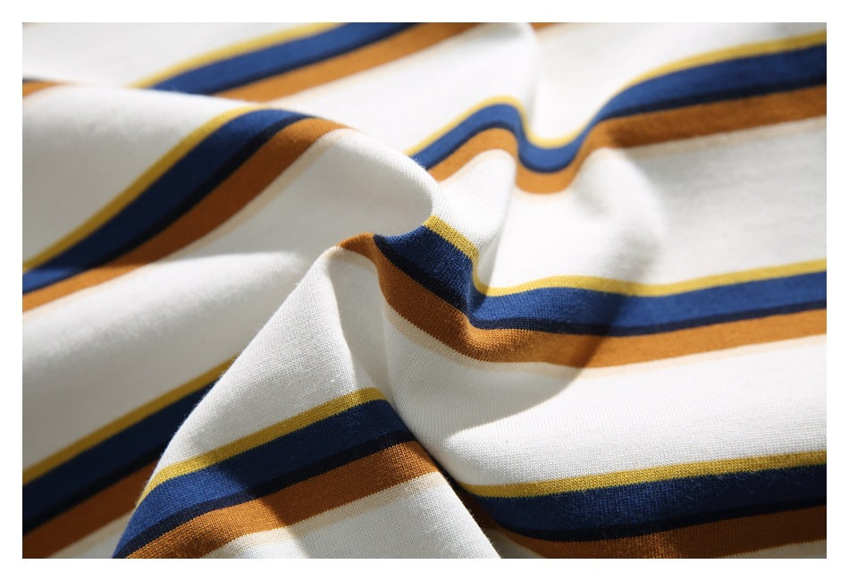 Close-up of white fabric with navy blue, mustard yellow, and brown horizontal stripes, gathered into soft folds.