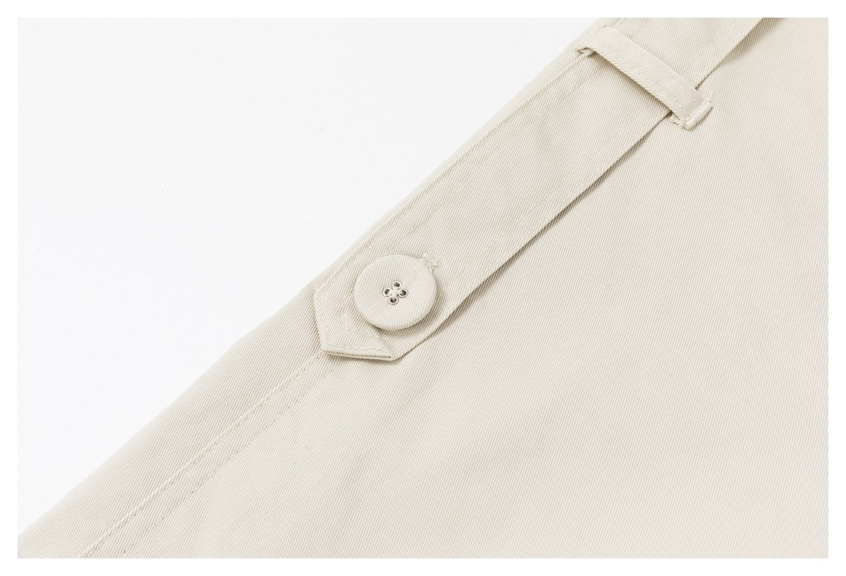 Close-up of a light beige coat button on a narrow tab, with a fabric loop and visible stitching.