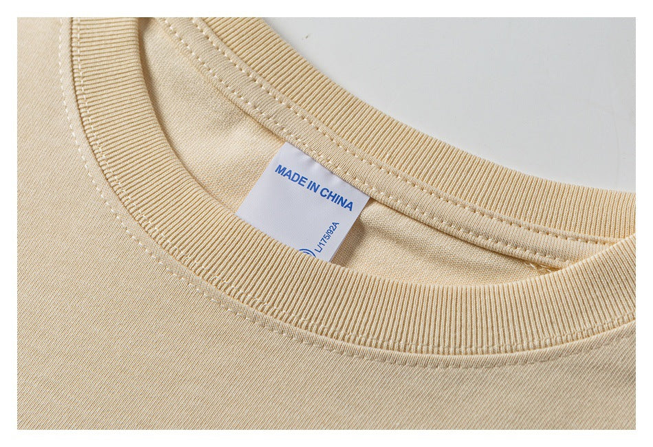 Close-up of a beige T-shirt’s ribbed crew neck and inner tag reading “MADE IN CHINA.”