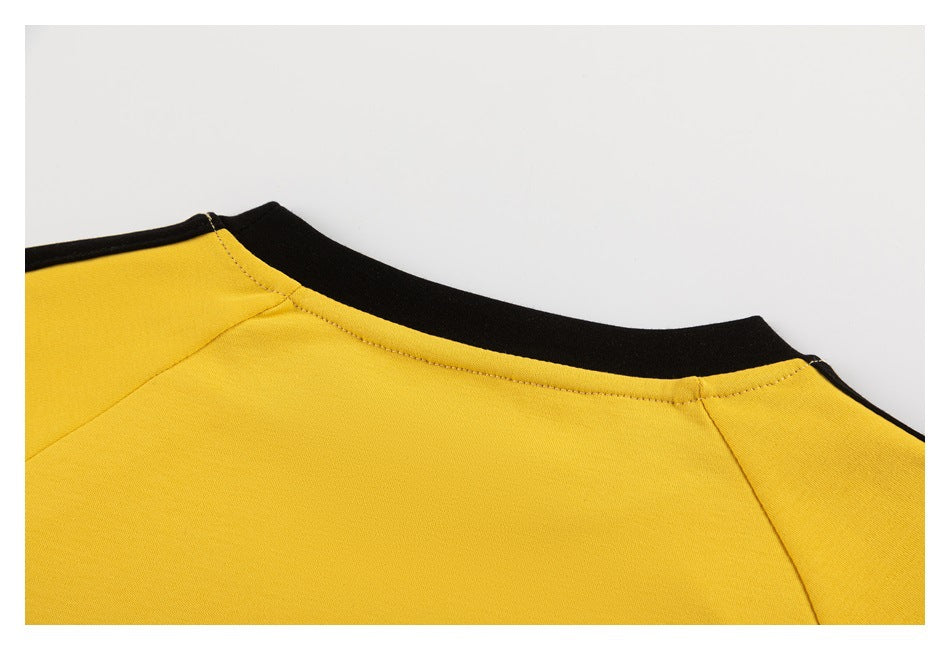 Close-up of the yellow shirt's black crew neckline and shoulder seams.