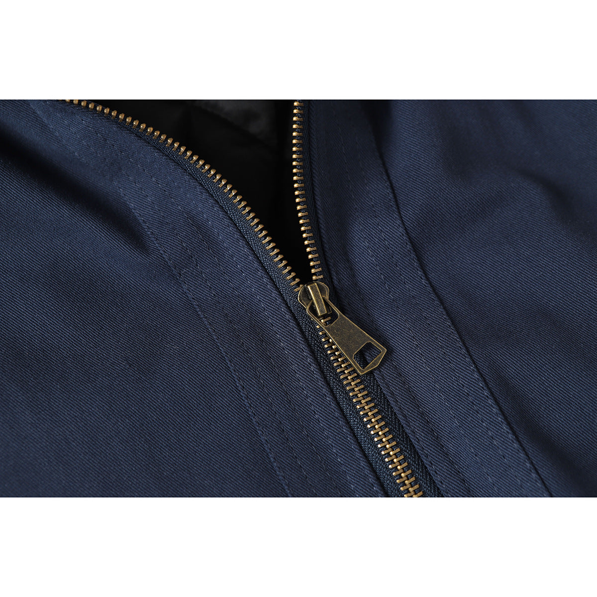 Close-up of the brass zipper and stitching on navy jacket fabric.