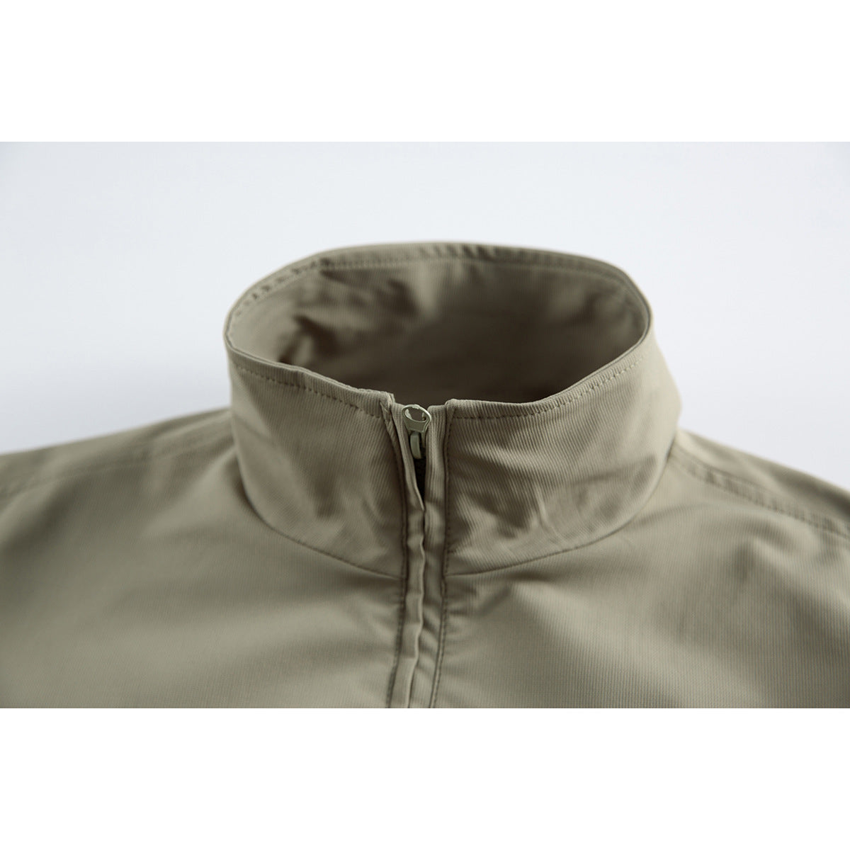 Close-up of an olive-gray jacket's tall stand collar and centered front zipper.