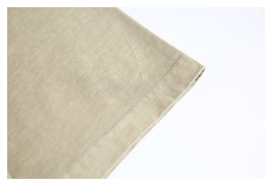 Close-up of a sand-beige T-shirt sleeve hem and double stitching.