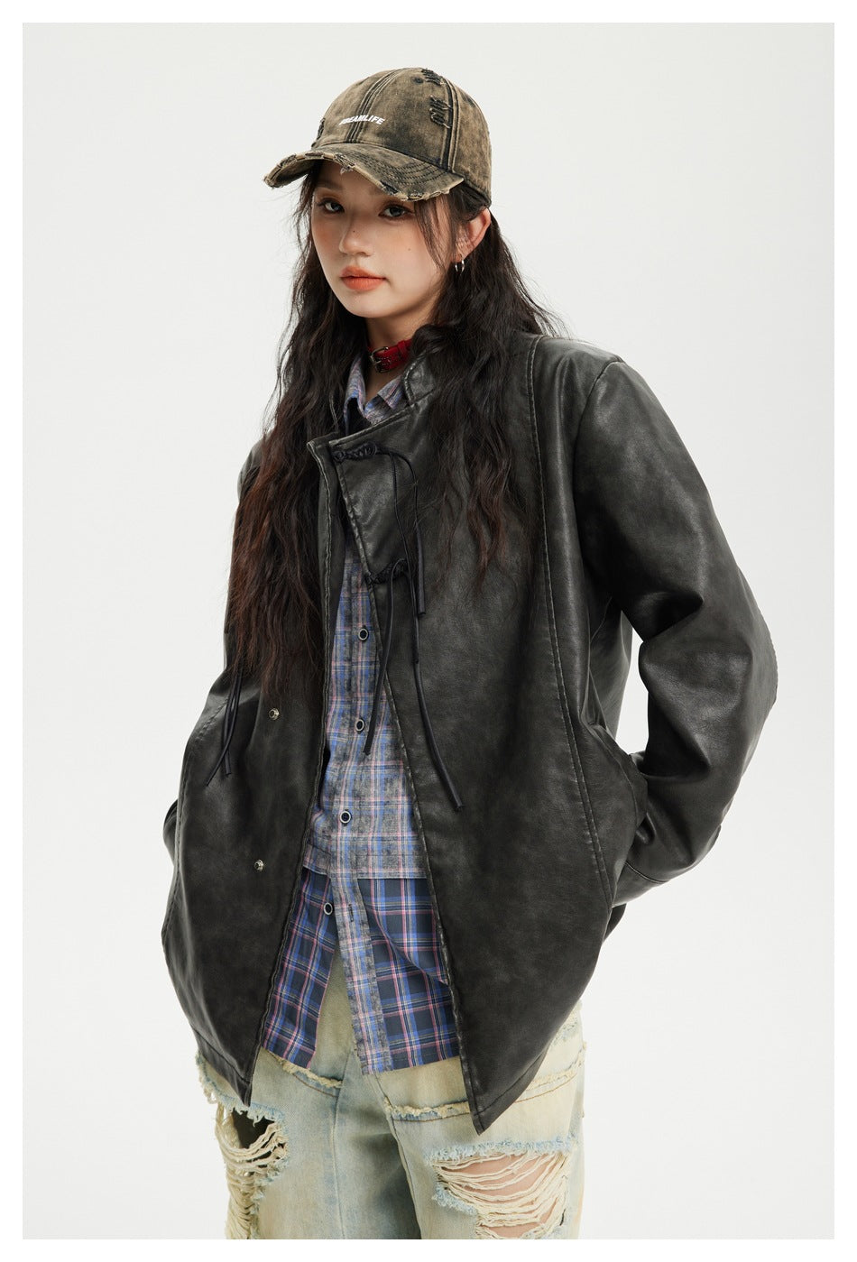 Model in a charcoal-black oversized jacket with toggle closures and a blue plaid shirt, shown at a three-quarter angle.
