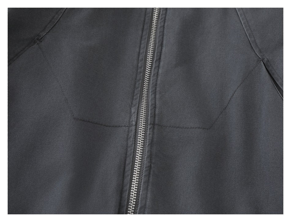 Close-up of the charcoal jacket's front zipper and angled pocket openings.