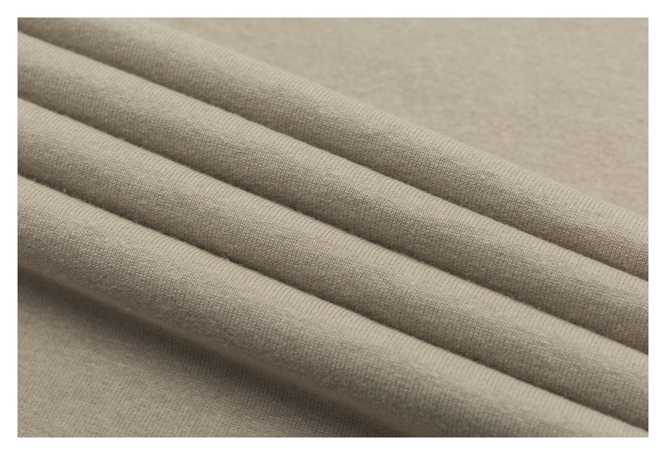 Close-up of beige fabric arranged in soft folds, showing its surface texture.
