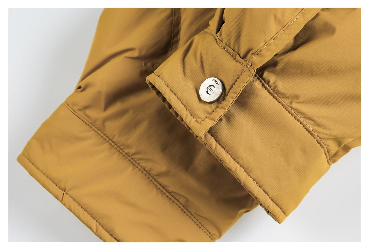 Close-up of a mustard-yellow jacket cuff with stitched panels and a silver snap fastener.
