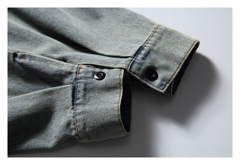 Close-up of two buttoned cuffs on a faded blue denim shirt laid on a light background.