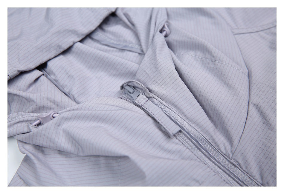 Close-up of a light gray jacket's front zipper, hood drawcord, and fine striped surface.