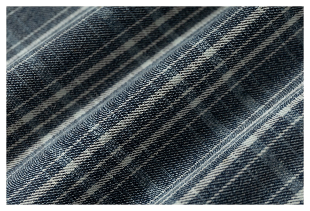 Macro view of the blue-gray plaid fabric weave and intersecting cream stripes.