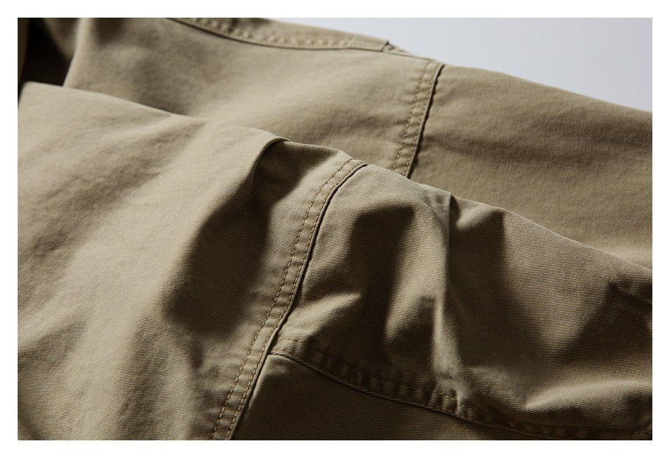 Close-up of overlapping khaki garment panels with stitched seams and folds.
