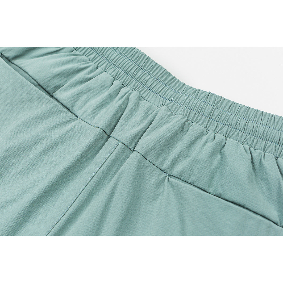 Close-up of aqua shorts showing the gathered elastic waistband and stitching.