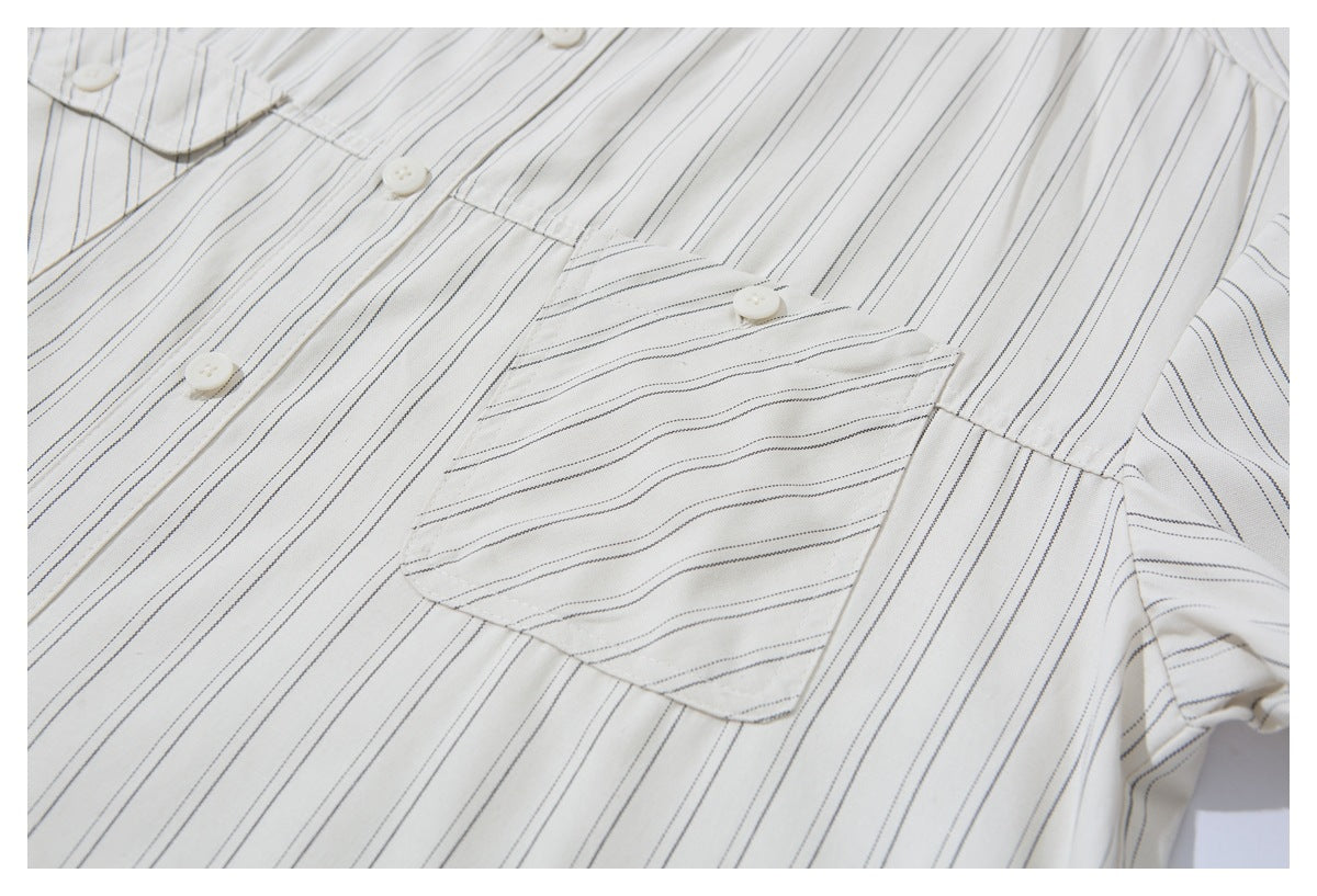 Close-up of an off-white shirt with fine dark pinstripes, white buttons, and a chest pocket.