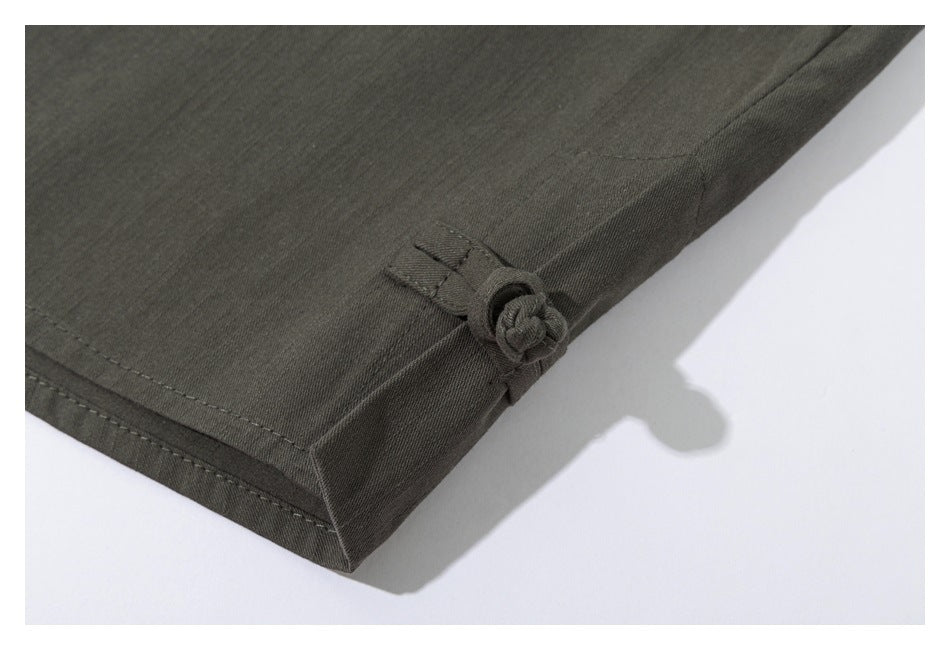 Close-up of a knotted fabric tab at the edge of a dark olive garment.