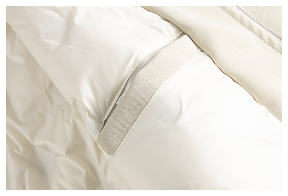 Close-up of a cream jacket showing a stitched diagonal opening and overlapping fabric panels.