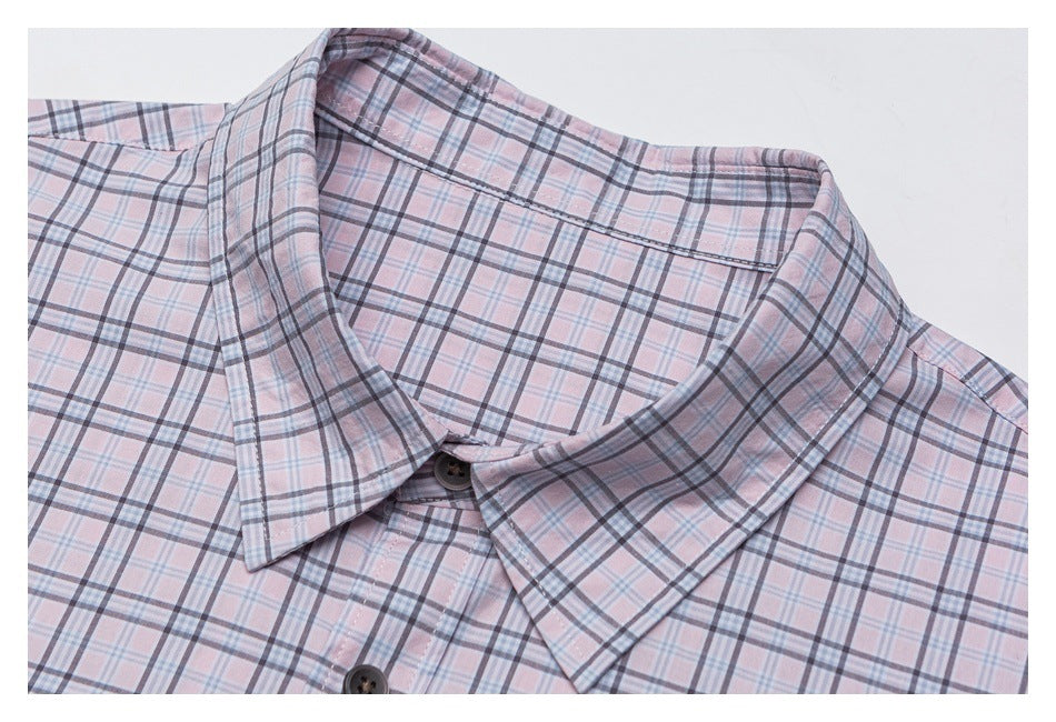 Close-up of a pale pink plaid shirt's pointed collar and dark buttons.
