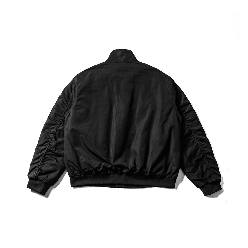 Back view of a black zip-up jacket with a stand collar, gathered sleeves, and ribbed cuffs and hem.