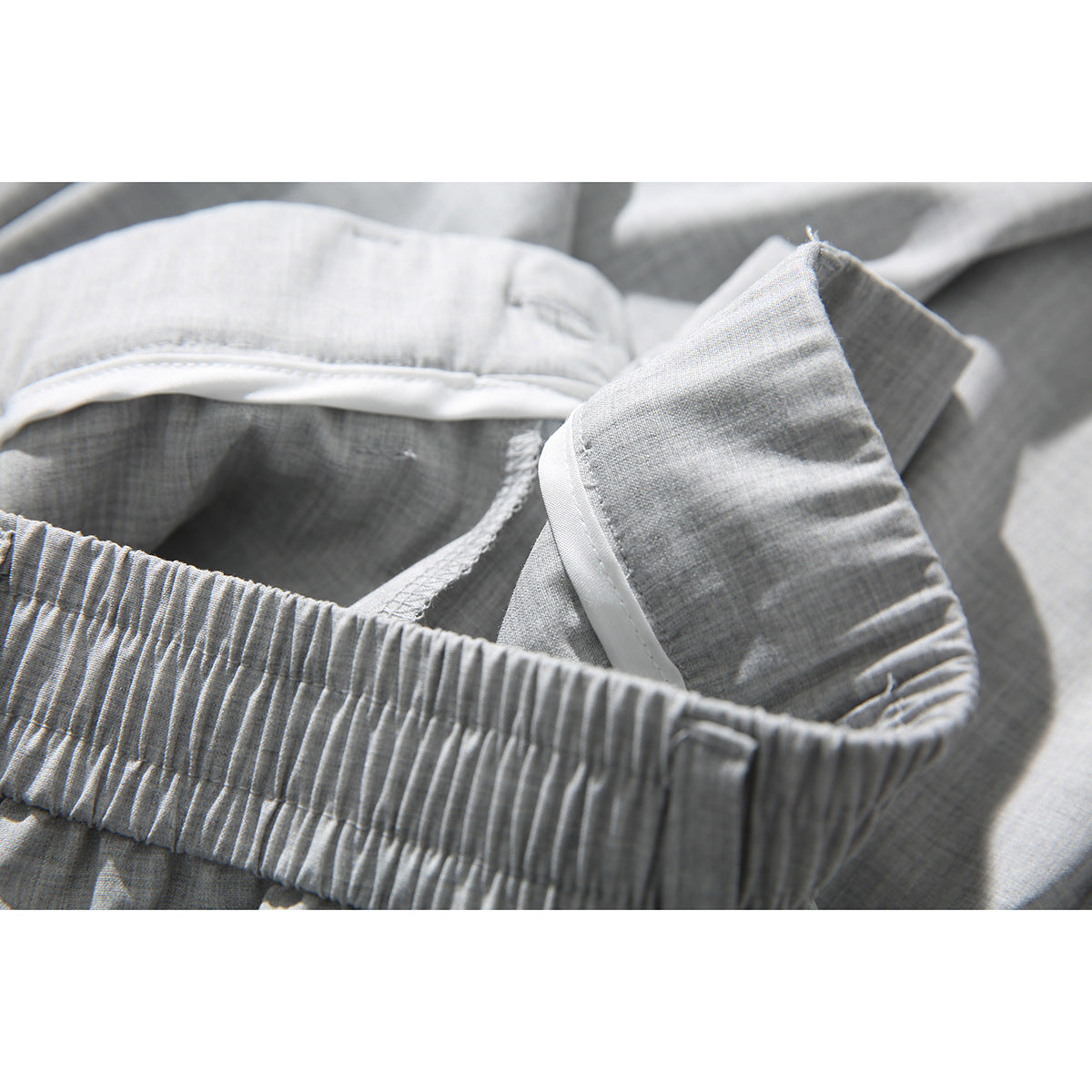 Close-up of the light gray shorts' gathered waistband and interior lining and seams.