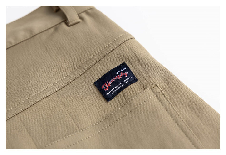 Close-up of khaki trousers showing stitched seams, a pocket edge, and a dark sewn-on label.