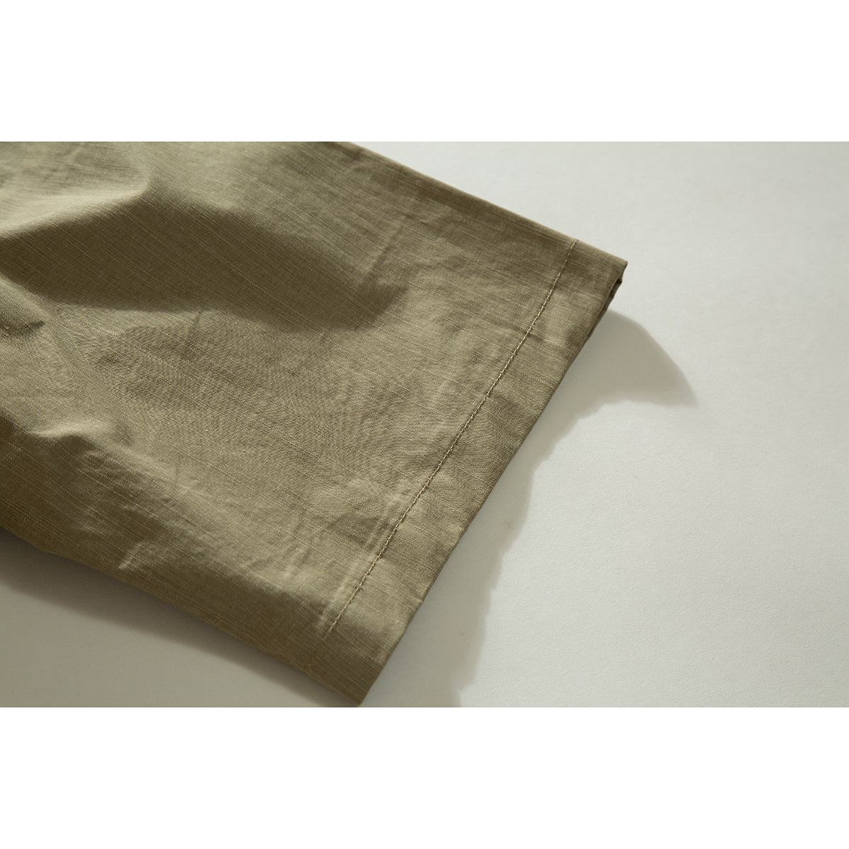 Close-up of the olive shirt's short sleeve and stitched hem.