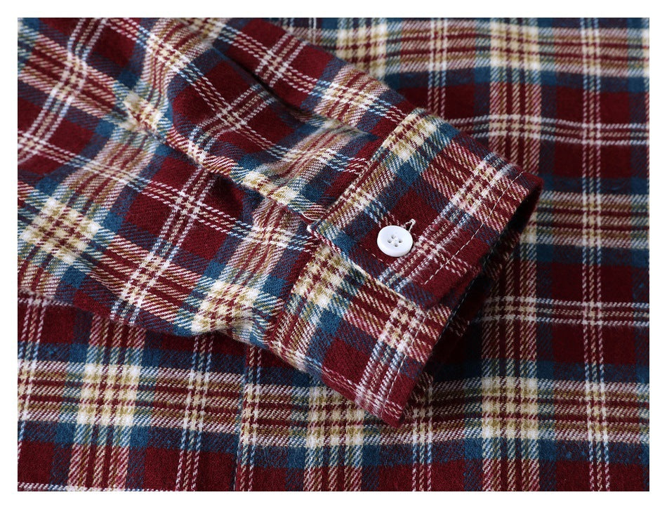 Close-up of a buttoned cuff on a burgundy, navy, cream, and tan plaid shirt.