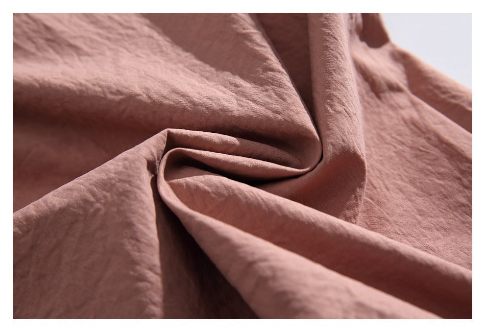 Macro view of dusty rose fabric draped into folds, showing its softly crinkled surface.