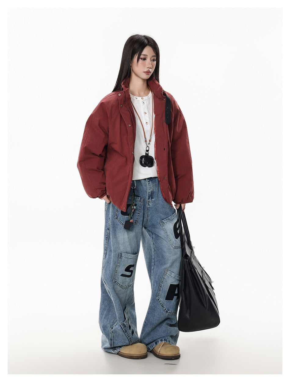 Full-length model wearing a burgundy oversized jacket and loose patchwork blue jeans.