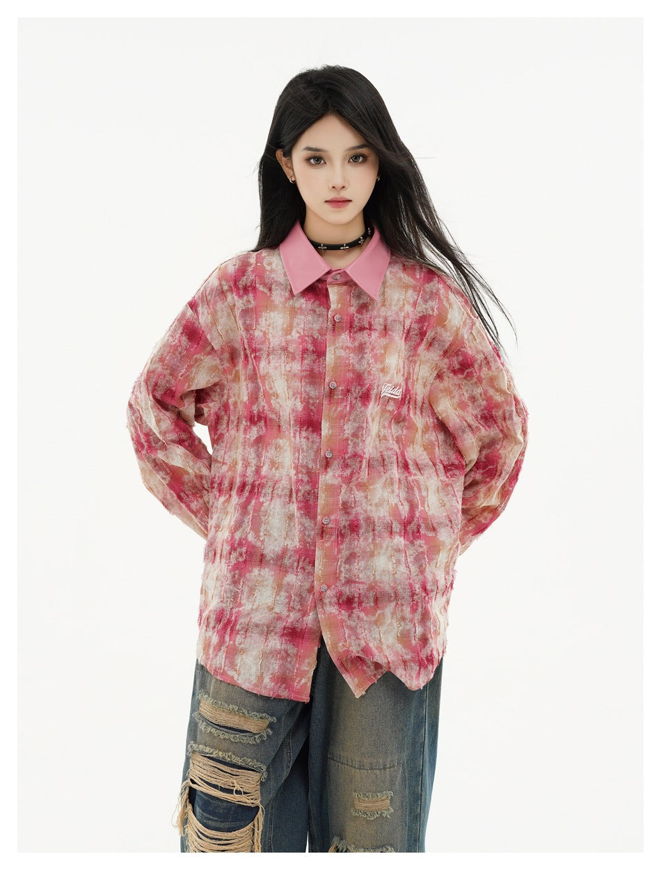 Model wearing a pink, cream and red abstract-print button-up shirt with a pointed pink collar and distressed jeans.