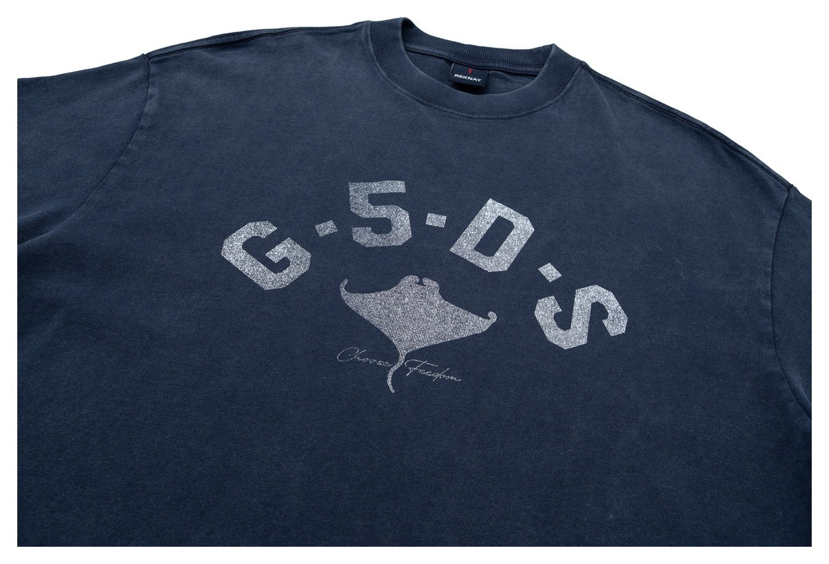 Front close-up of a navy short-sleeve crew-neck shirt with distressed white lettering and a manta ray graphic.