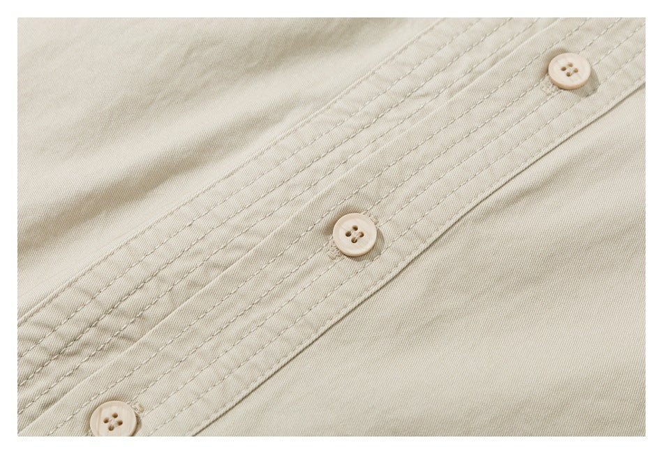 Close-up of beige fabric with a stitched placket and three light-colored buttons.