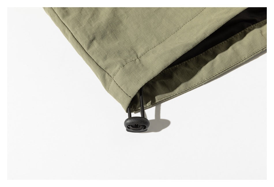 Close-up of an olive-green jacket hem with an adjustable drawcord and toggle.