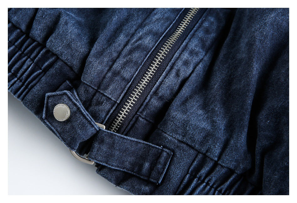 Close-up of a dark blue jacket hem with a central zipper and adjustable tab fastened by a metal button.