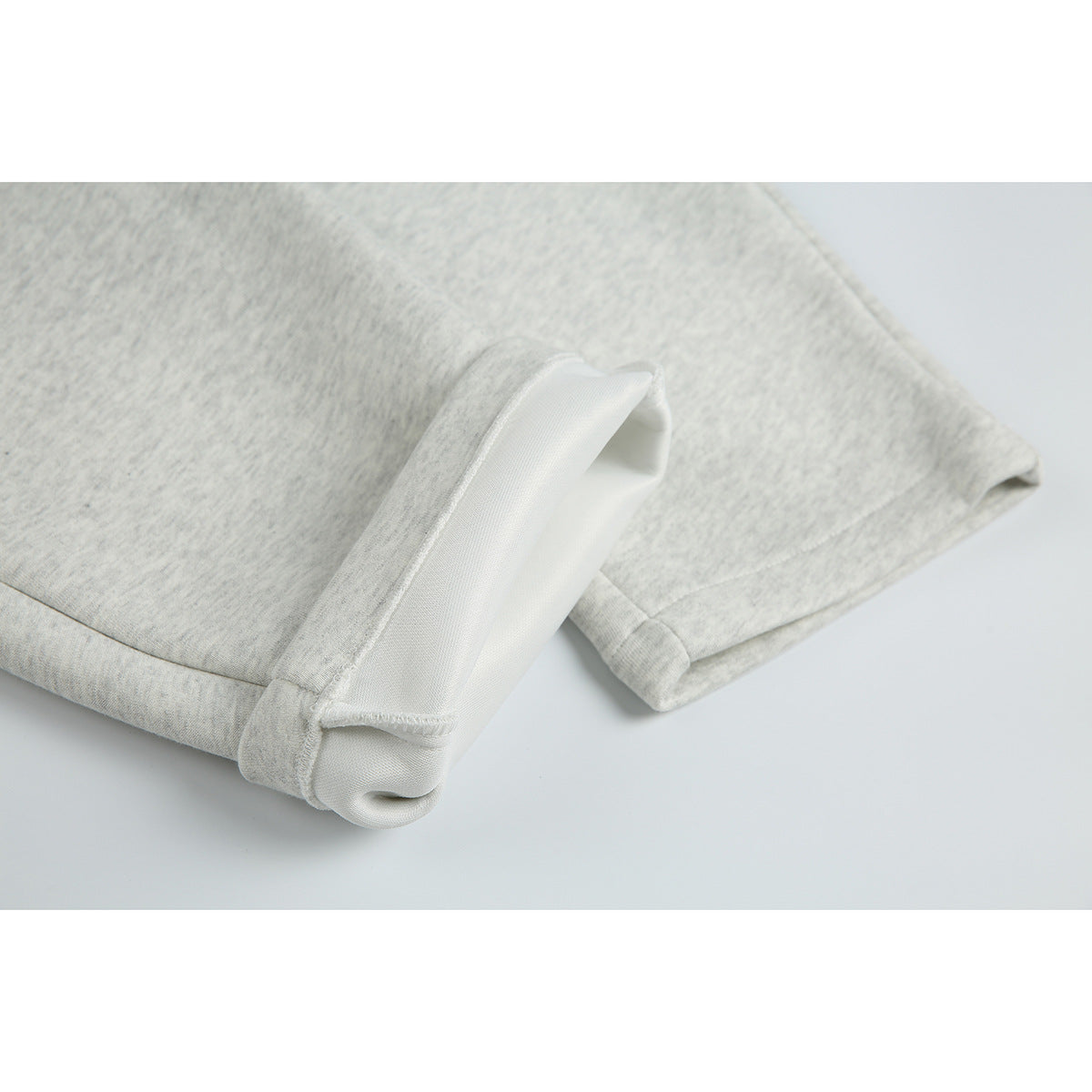 Close-up of a light gray marl sweatpant leg with the cuff turned back to show its inner side.