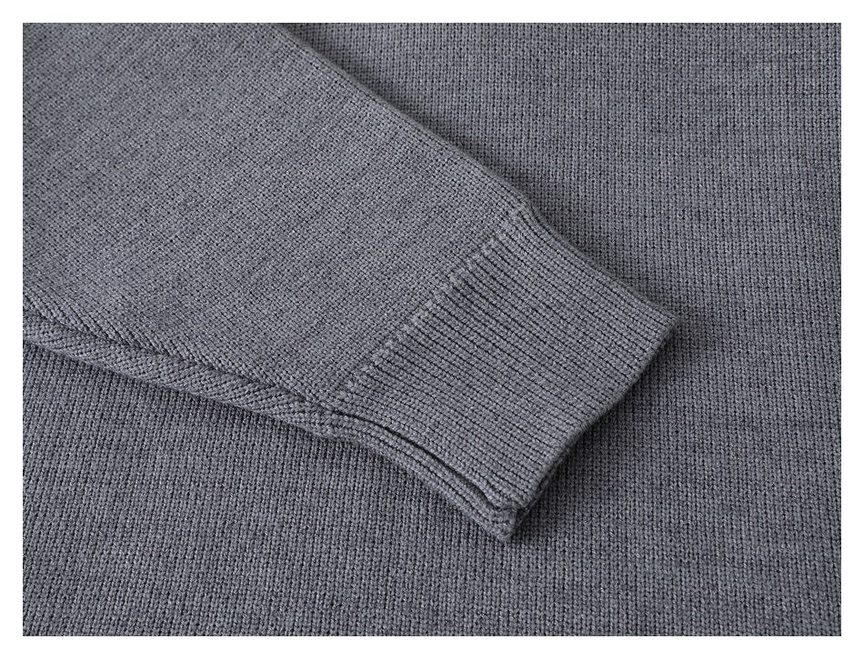 Close-up of a gray knitted sleeve ending in a ribbed cuff against the sweater body.