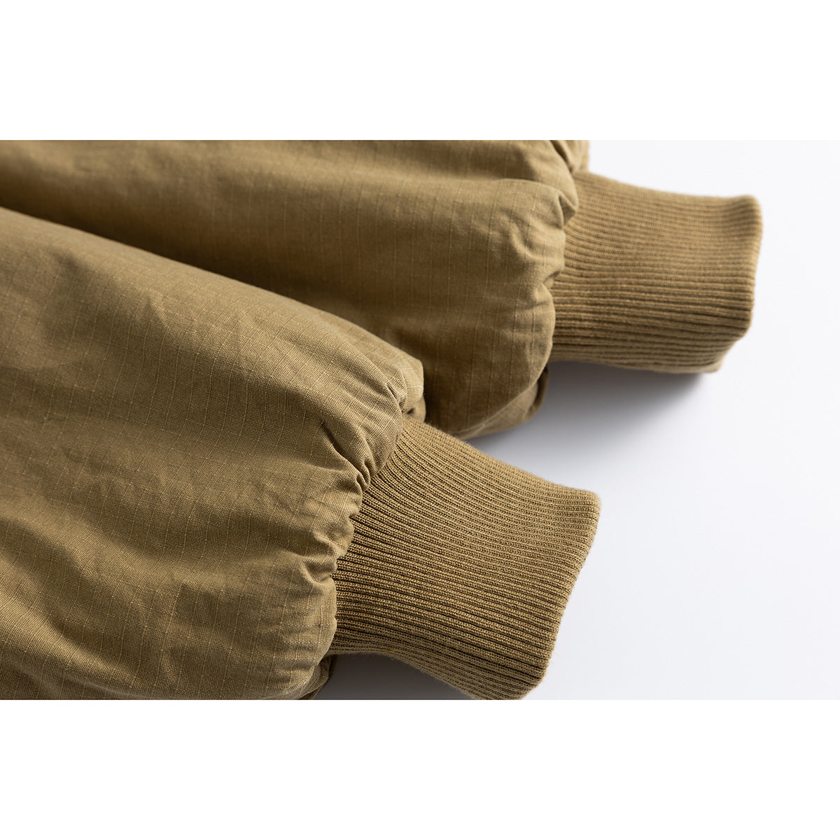 Close-up of two olive-brown jacket sleeves with ribbed knit cuffs.