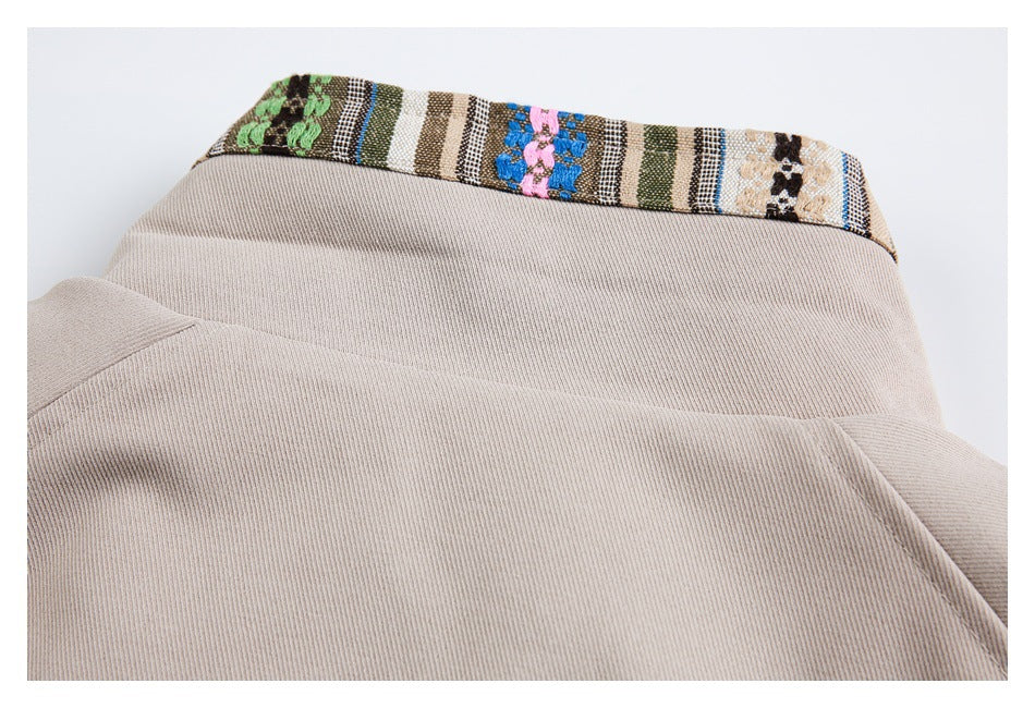 Close-up of a beige garment neckline finished with a multicolored woven trim.