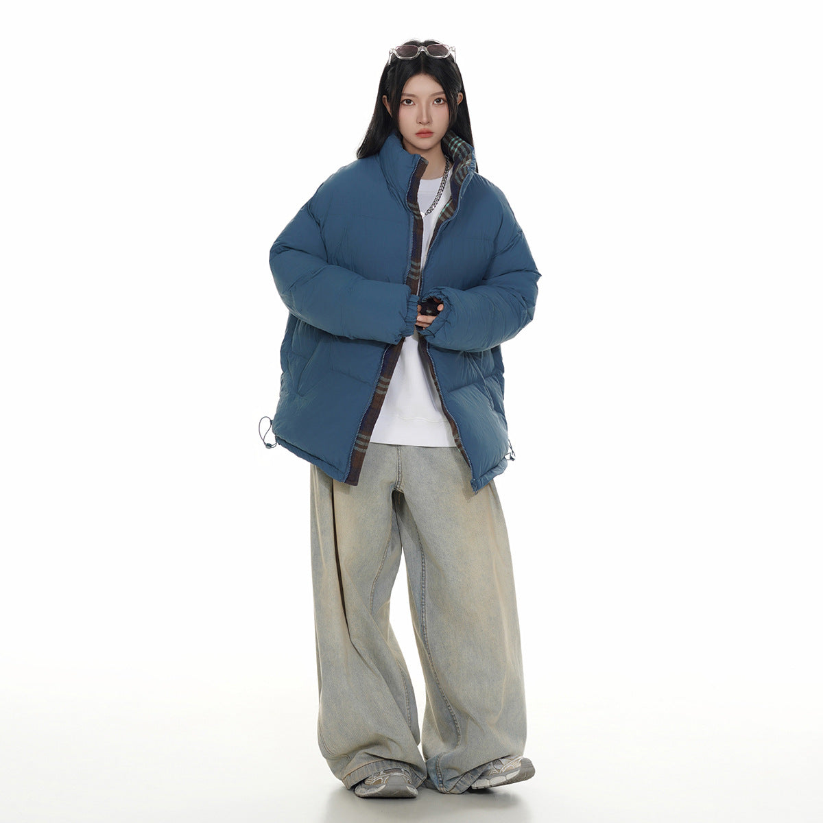 Full-length model wearing a blue puffer jacket with plaid trim visible inside the open front and collar.