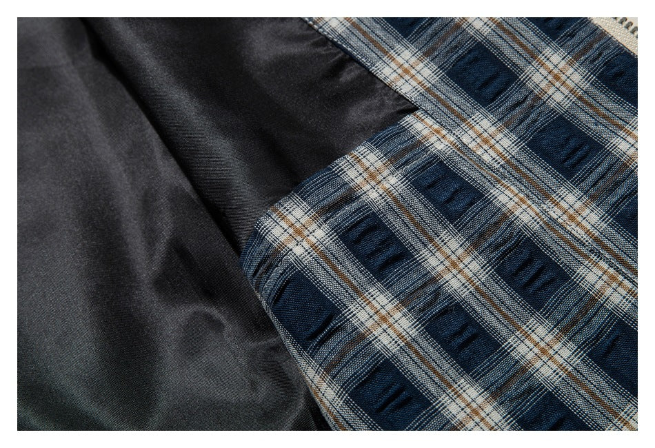 Close-up of dark blue, gray, and tan plaid lining beside a dark garment panel.