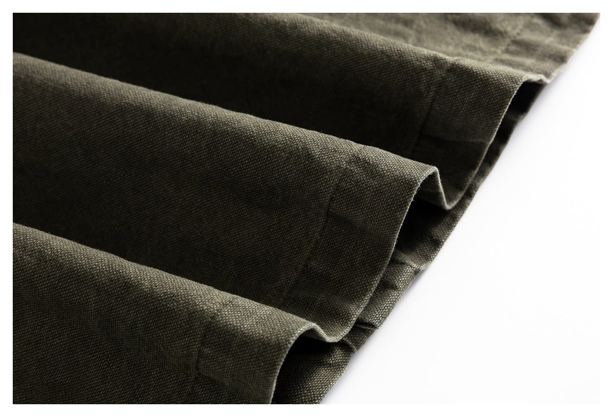 Close-up of dark olive fabric arranged in folds, showing a folded edge and subtle woven texture.