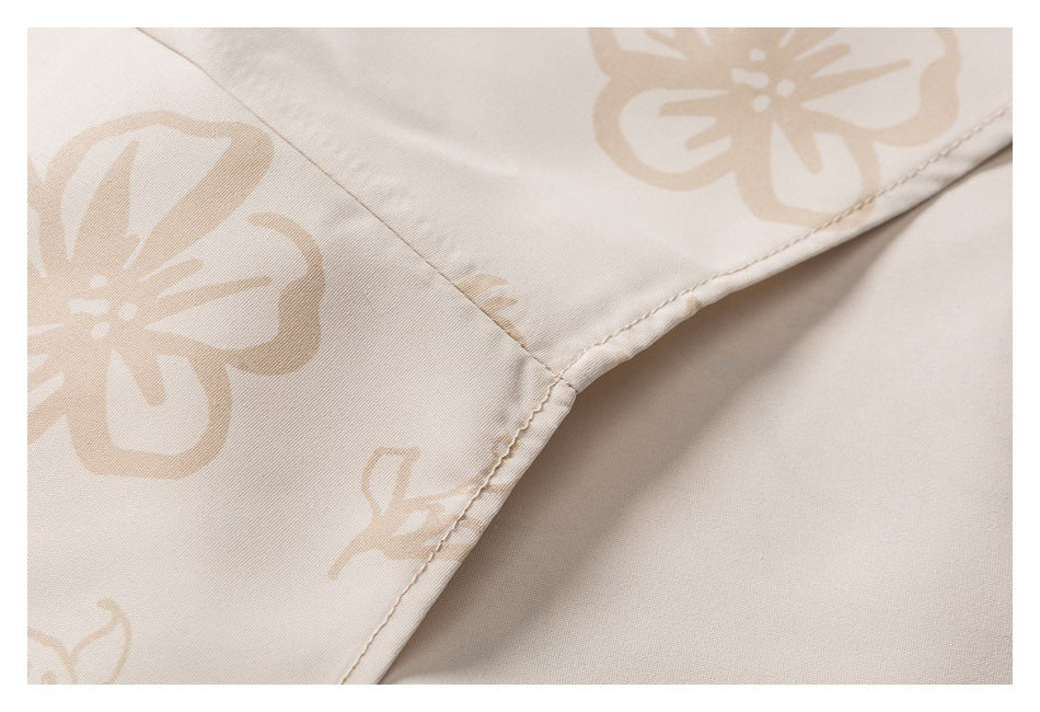 Close-up of the stitched edge of cream fabric with a large beige floral pattern.