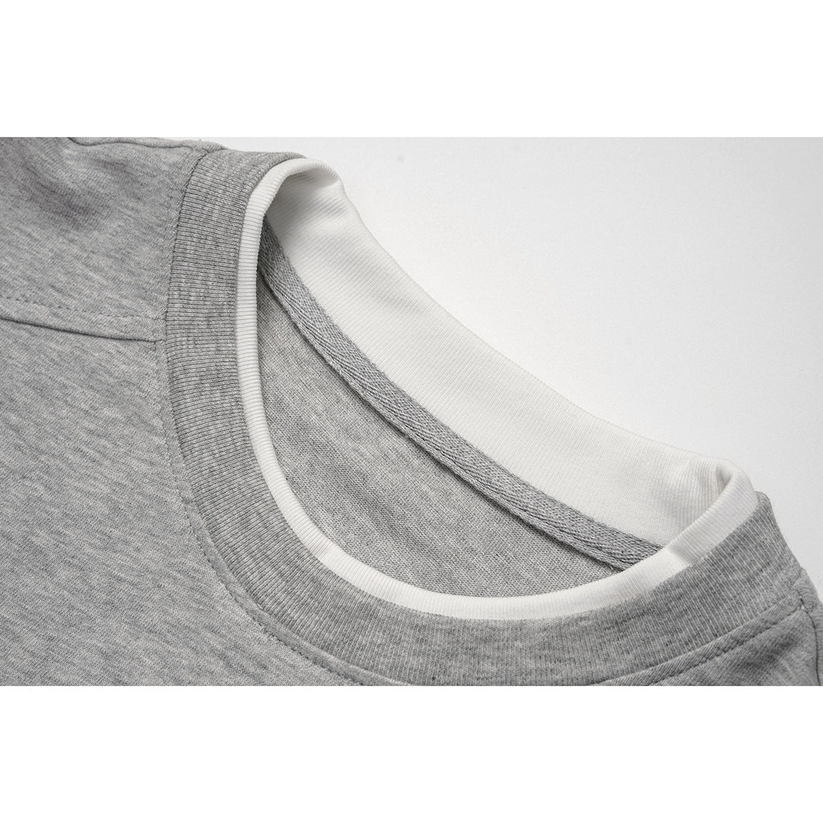 Close-up of a heather gray sweatshirt’s crew neckline, showing white inner ribbing and stitched seams.