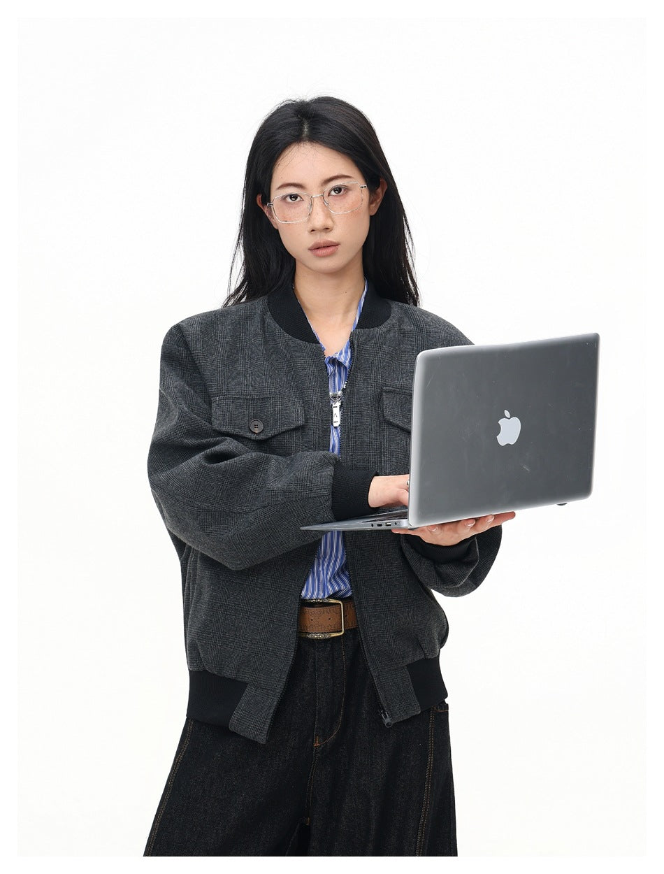 Model in gray zip bomber jacket with black ribbed trim and chest pockets, holding an open laptop
