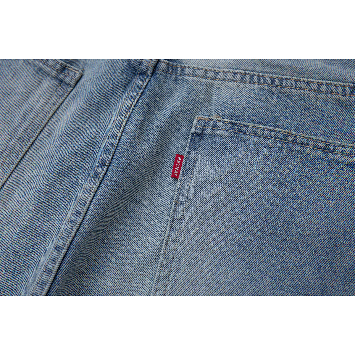 Close-up of a back pocket on light blue jeans with a small red sewn-in label.