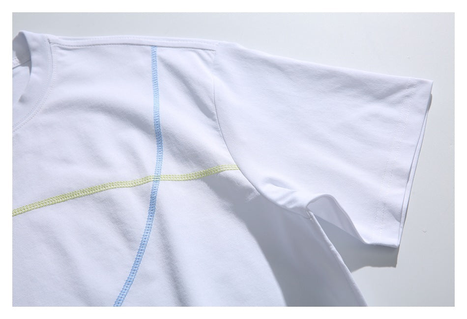 Close-up of a white T-shirt sleeve and body with curved blue and pale yellow-green overlock seams.