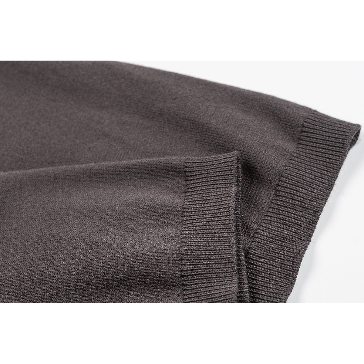 Close-up of a taupe knit top showing its sleeve and wide ribbed cuff.