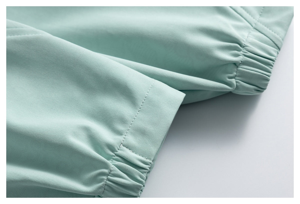 Close-up of a mint garment sleeve with a gathered elastic cuff and stitched seam.