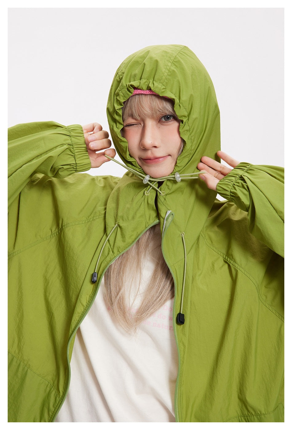 Close-up of a model wearing a lime-green jacket with the hood cinched around the face.